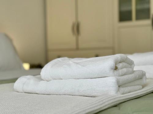 a stack of white towels sitting on a bed at Kallithea Central Apartment in Kallithea Halkidikis