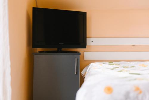 a flat screen tv on top of a dresser next to a bed at Riverside • cabine in Gălăuţaş