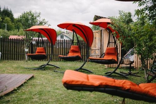 a group of chairs with red umbrellas in a yard at Riverside • cabine in Gălăuţaş