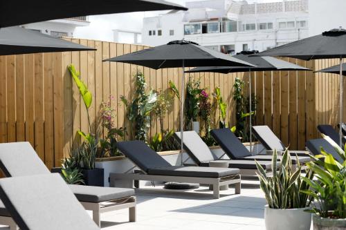 szereg leżaków i parasoli na patio w obiekcie Stic Urban Hotel & SPA w mieście San Antonio