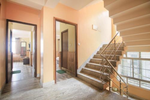 einen Flur mit Treppe in einem Haus mit orangefarbenen Wänden in der Unterkunft Capital O Saramsa Enclave in Tādong