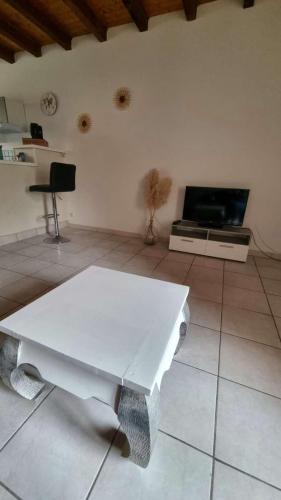 Il comprend un salon doté d'une table blanche et d'une télévision. dans l'établissement Gite du soleil levant jura, à Gevingey