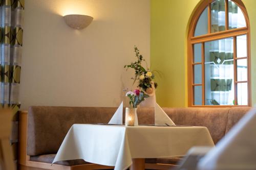 a white table with a vase of flowers on it at Ferienwohnungen am Geiseltalsee in Braunsbedra