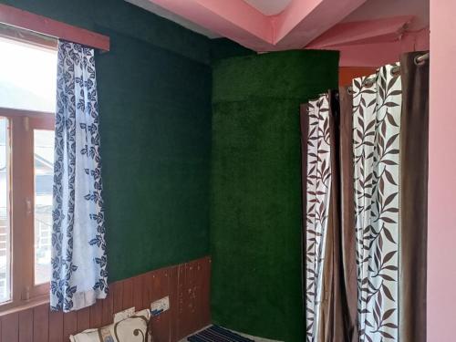a room with green walls and windows with curtains at ROOP MOUNTAIN HOMESTAY No Parking in Manāli