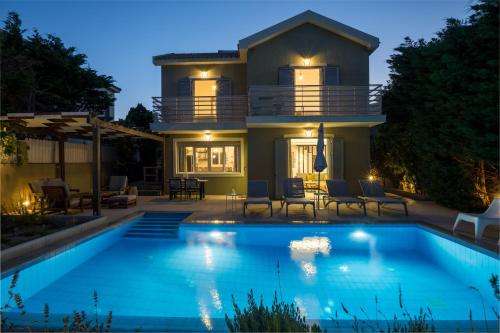 a house with a swimming pool in front of a house at Beachfront Villa Alexandra in Skala Kefalonias