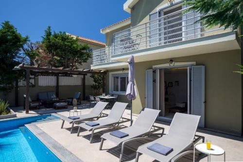 a group of chairs sitting next to a swimming pool at Beachfront Villa Alexandra in Skala Kefalonias