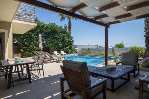 a patio with a table and chairs and a swimming pool at Beachfront Villa Alexandra in Skala Kefalonias