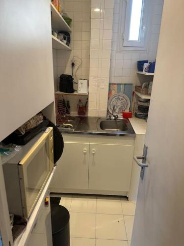 une petite cuisine avec un évier et un micro-ondes dans l'établissement Lumineux appartement de 47m2 dans le 17eme, à Paris