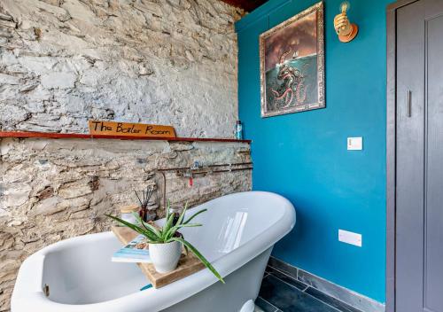 a bathroom with a white tub and a blue wall at Easter Cottage - Berrynarbor in Berrynarbor