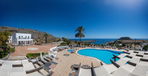 a resort with a pool and chairs and the ocean at KRANA Hotel in Líndos
