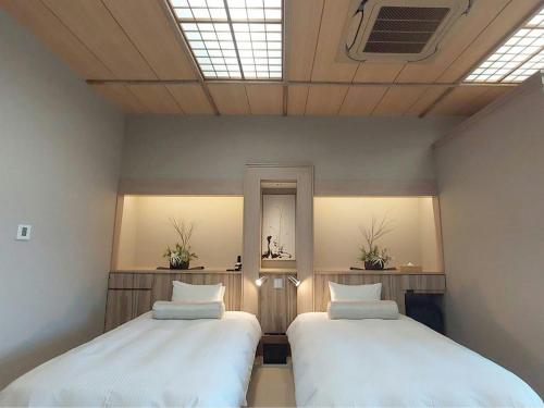 two beds in a room with two windows at Ikoi no Mura Heritage Minoyama in Minano