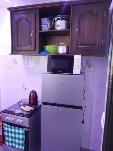 una cocina con un microondas encima de un refrigerador en Maison cité, en Cotonou