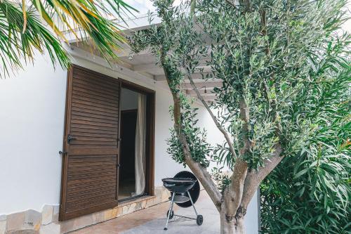 a grill next to a tree next to a house at Case Vacanze Il Sogno 2 in Porto Pino