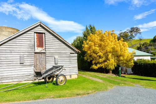 an old house with a wheelbarrow in front of it at Mountain View Tilba Tilba - Glamping in Tilba Tilba