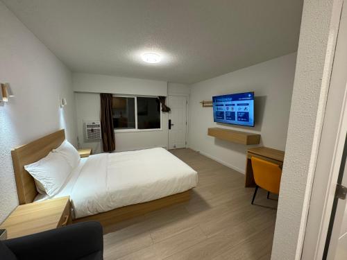 een slaapkamer met een bed, een bureau en een televisie bij Inntowne Motel in Hope