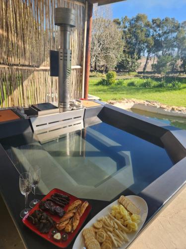 a glass table with a plate of food and wine at Villa Wal Farmstay in Hartebeest Rivier