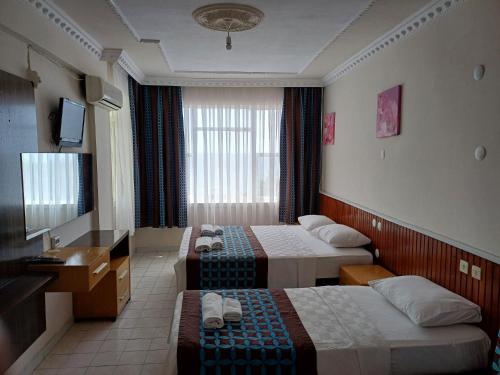 Una habitación de hotel con dos camas y un televisor. en Lila butık hotel alanya, en Alanya