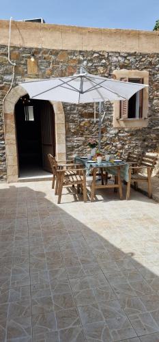 a picnic table with an umbrella in front of a building at Yiannis Village house in Asklipiḯon