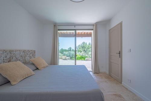 VILLA VOGA- Luxury family holidays Aix-en-Provence في إيغيليه: غرفة نوم بيضاء بسرير كبير وباب زجاجي منزلق