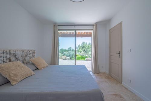 a white bedroom with a large bed and a sliding glass door at VILLA VOGA- Luxury family holidays Aix-en-Provence in Éguilles
