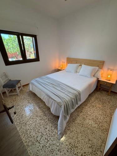 um quarto com uma grande cama branca e 2 janelas em Can Moya em Sant Ferran de Ses Roques