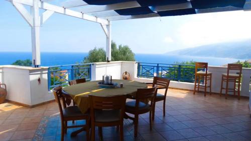 eine Terrasse mit einem Tisch und Stühlen auf dem Balkon in der Unterkunft Sunset Apartments in Évdilos