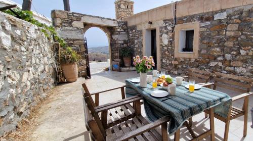 Yiannis Village house في Asklipiḯon: طاولة وكراسي على فناء بجدار حجري