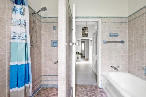 ein Badezimmer mit Badewanne, Dusche und Waschbecken in der Unterkunft Cozy Queen Room - Nearby Transport & Shop - Shared Bathroom in Killara