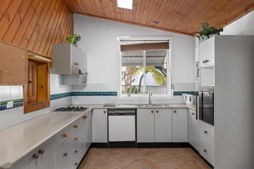 a kitchen with white cabinets and a window at Quadruple Ensuite Room - Nearby Stations & Shops in Regents Park