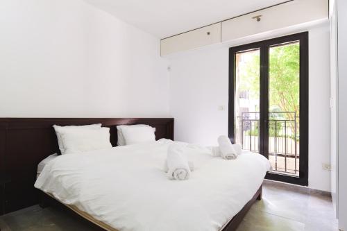 a bedroom with a large white bed and a window at 2 BR next to Old City with Patio by FeelHome in Jerusalem