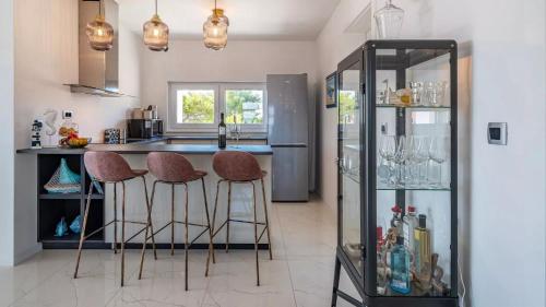 a kitchen with a bar with stools and a refrigerator at Villa Bura in Barbat na Rabu