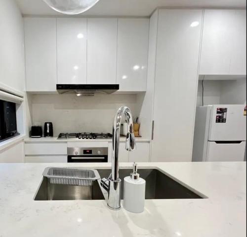 a white kitchen with a sink and a faucet at Boutique House 3B with Garden in Melbourne