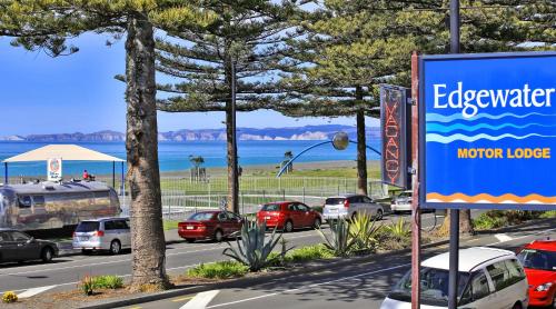 a sign for a motor lodge next to a road with cars at Edgewater Motor Lodge in Napier