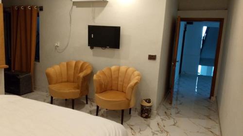 um quarto com duas cadeiras e uma televisão na parede em Hotel Crown Palace em Murree