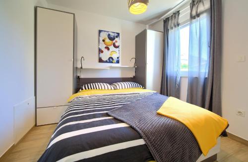 um quarto com uma cama grande com lençóis amarelos e cinzentos em Apartment SARA em Krk