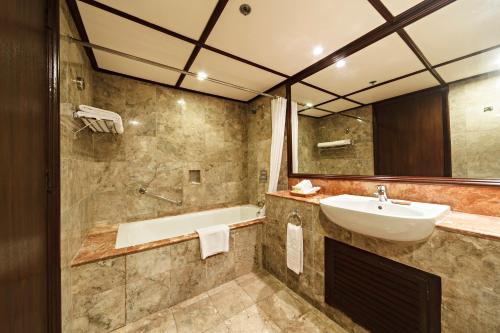 uma casa de banho com um lavatório e uma banheira em Waterfront Airport Hotel and Casino em Mactan