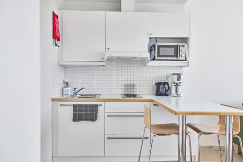 a kitchen with white cabinets and a table and chairs at Töölö Towers in Helsinki