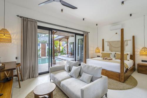 een slaapkamer met een kingsize bed en een bank bij Sicilia Villa by DH Ubud in Ubud