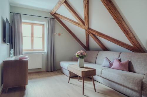 a living room with a couch and a window at Romantik Spa Hotel Elixhauser Wirt in Elixhausen