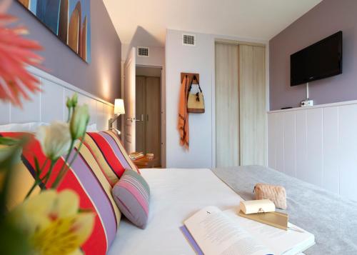 um quarto de hotel com uma cama com livros e uma televisão em Résidence Pierre & Vacances Premium Haguna em Biarritz