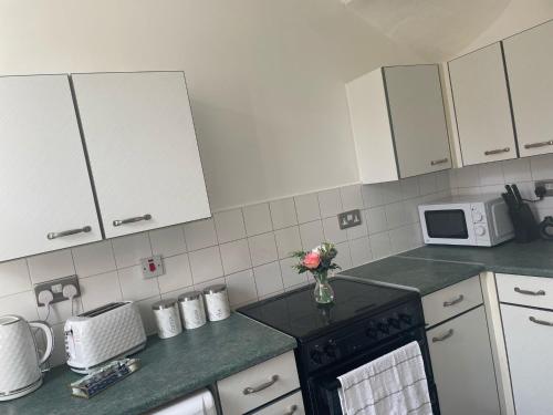 eine Küche mit weißen Schränken und einem schwarzen Herd mit Backofen in der Unterkunft Clifton Home - Newly refurbished - Perfect for contractors! in Killingbeck