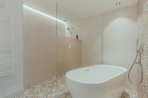 a white bathroom with a tub and a shower at Romantik Spa Hotel Elixhauser Wirt in Elixhausen