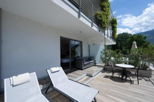 a patio with white chairs and a table on a balcony at Hotel Bellariva in Riva del Garda