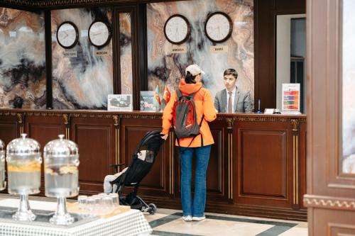 a woman standing in front of a counter with a man at Grand Hotel Baku Central Park in Baku