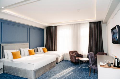 ein Hotelzimmer mit einem großen Bett und Stühlen in der Unterkunft Grand Hotel Baku Central Park in Baku