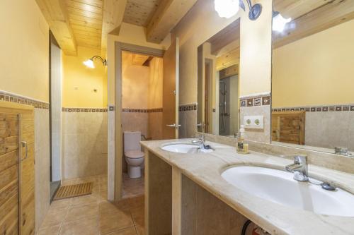a bathroom with two sinks and a toilet at El Refugi De Rubinat in Sant Antolí i Vilanova