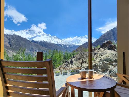 a table and chair on a balcony with a view of mountains at Ambiance Resort Hunza in Hunza