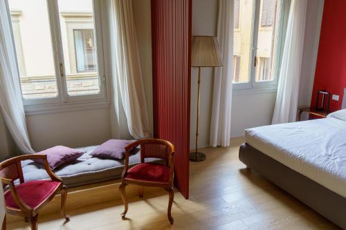 a bedroom with two chairs and a bed and windows at Signoria n&deg;5 in Florence