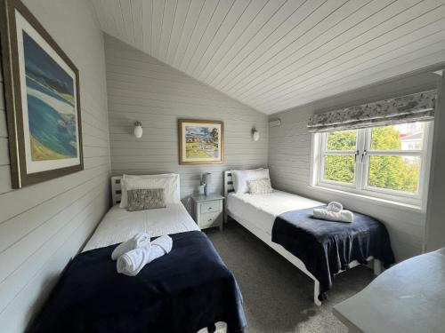 um quarto com 2 camas e uma janela em Holly Blue - Cosy wooden lodge Kippford em Dalbeattie