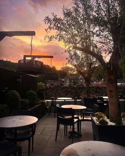 a patio with tables and chairs with a sunset in the background at The Inn At Grasmere in Grasmere